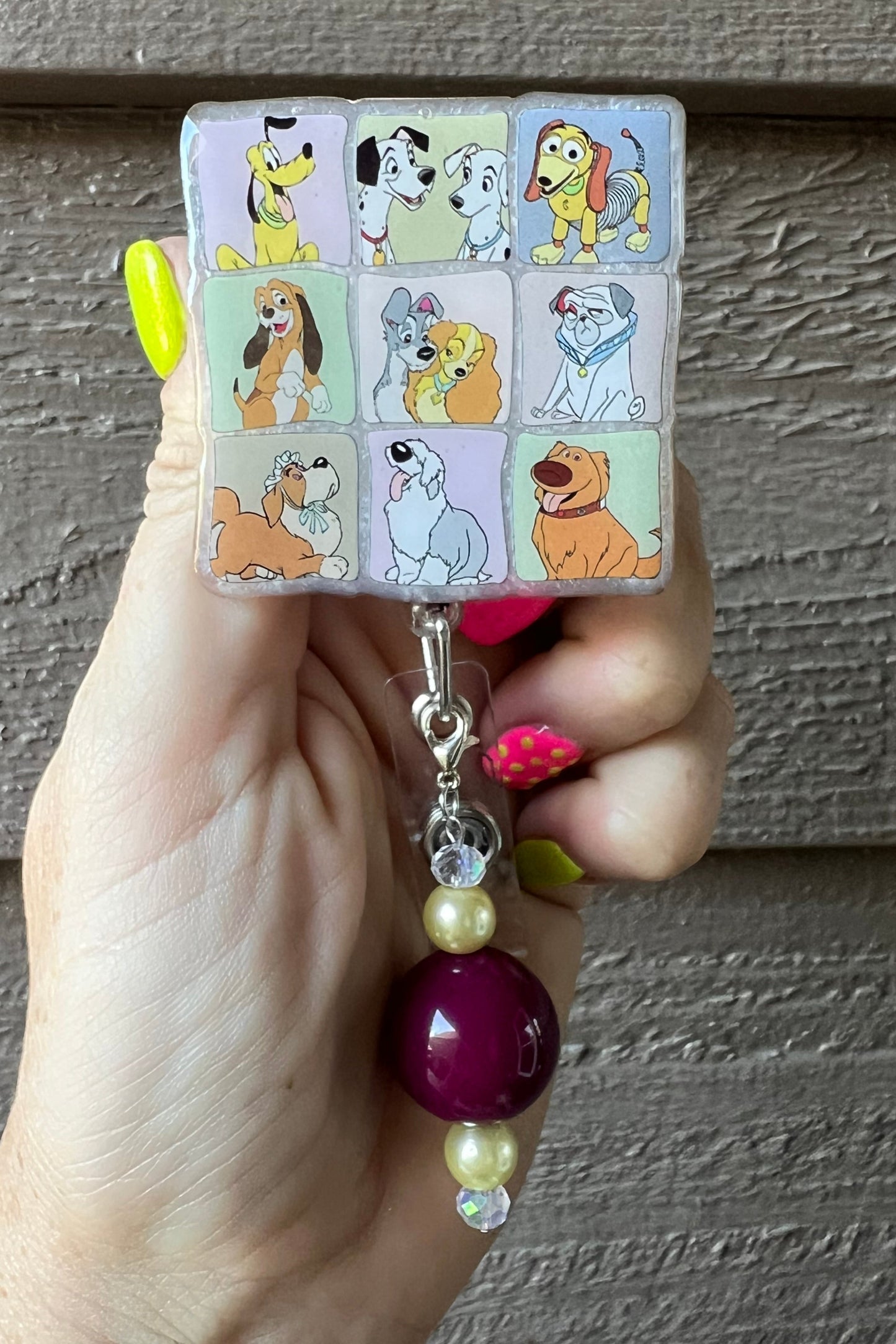 Hand holding disney dog badge reel with 9 different dogs displayed.