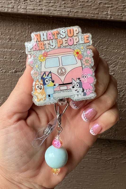 Bluey-themed glitter badge reel with "What's Up Party People" text and pastel pink van, with light blue and pink beaded dangle