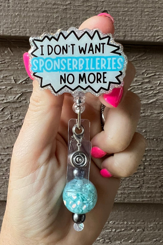 Badge reel with the quote "I don't want sponserbileries no more" and a glitter border, featuring a teal and black beaded dangle.