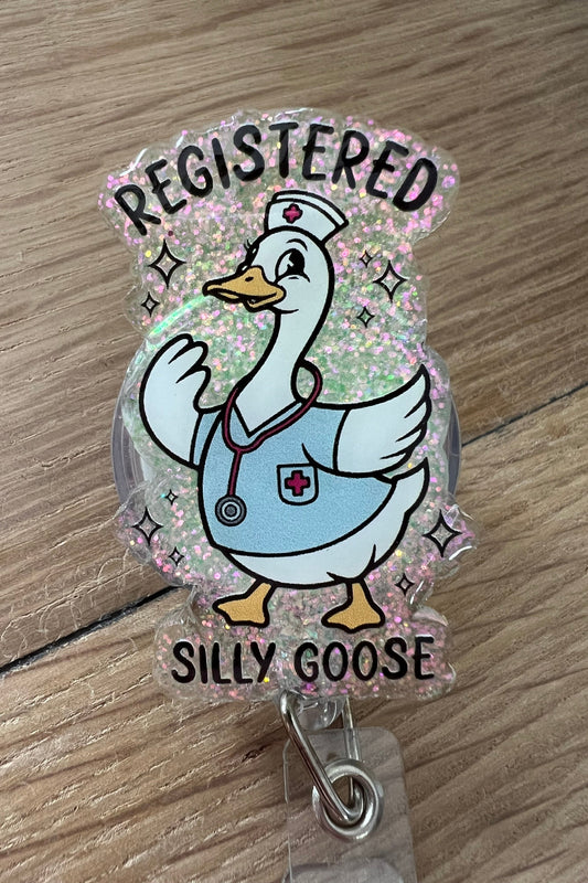 Funny nurse badge reel with a cartoon goose in scrubs and the phrase “Registered Silly Goose” on glitter background
