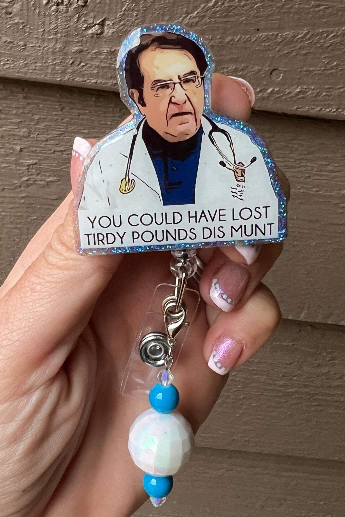 Funny badge reel featuring Dr. Now with the quote “You could have lost tirdy pounds dis munt” and a glittery edge
