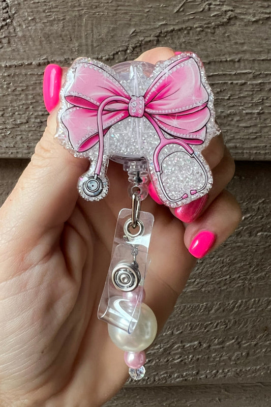 Pink Bow Badge Reel with Stethoscope on soft pearl glitter with pearl and pink beaded dangle.