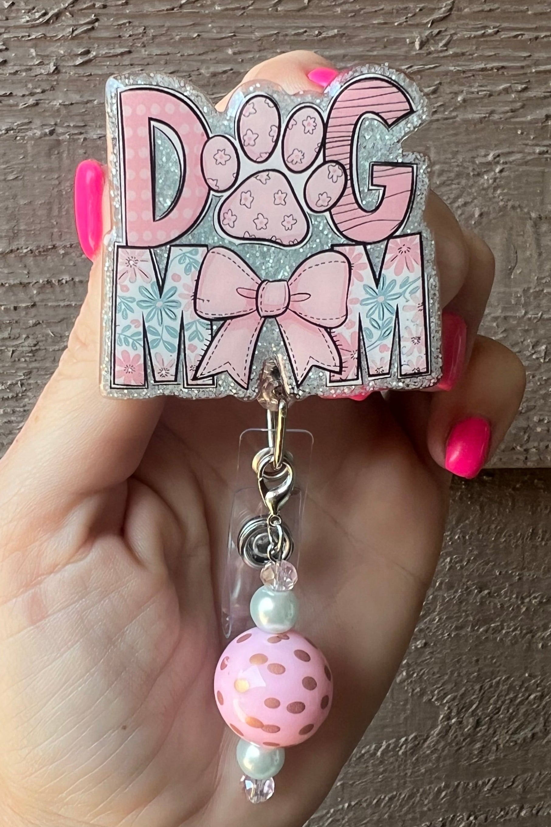 Pink Glitter badge reel with the words "Dog Mom," paw print and bow design, featuring a pink polka dot and pearl beaded dangle.
