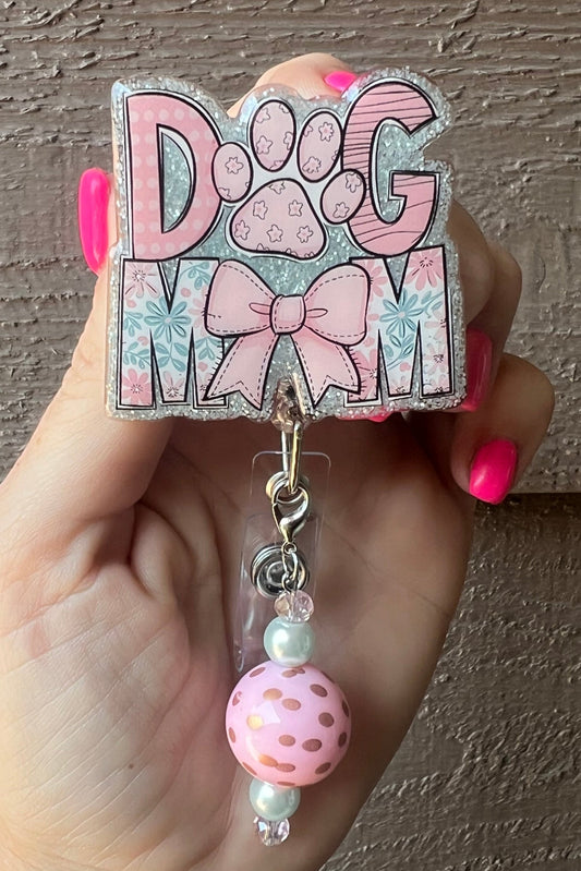 Pink Glitter badge reel with the words "Dog Mom," paw print and bow design, featuring a pink polka dot and pearl beaded dangle.