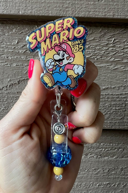 Super Mario badge reel on blue glitter background with coordinating badge bling.