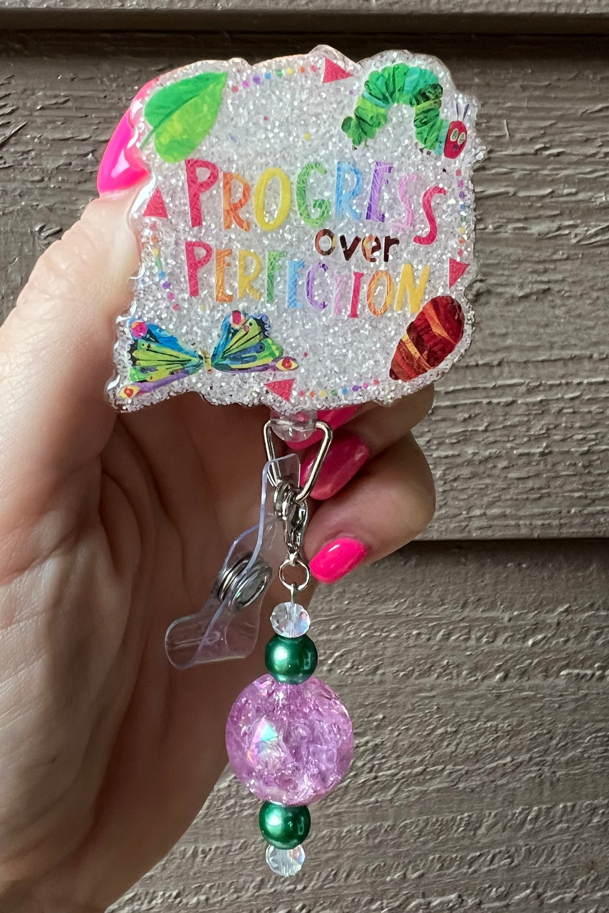 Soft Glitter Badge Reel that says "Progress over Perfection" with illustrations inspired by The Very Hungry Caterpillar.