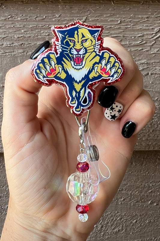 Hand holding badge reel featuring the Florida Panther logo with red glitter border and coordinating badge bling.