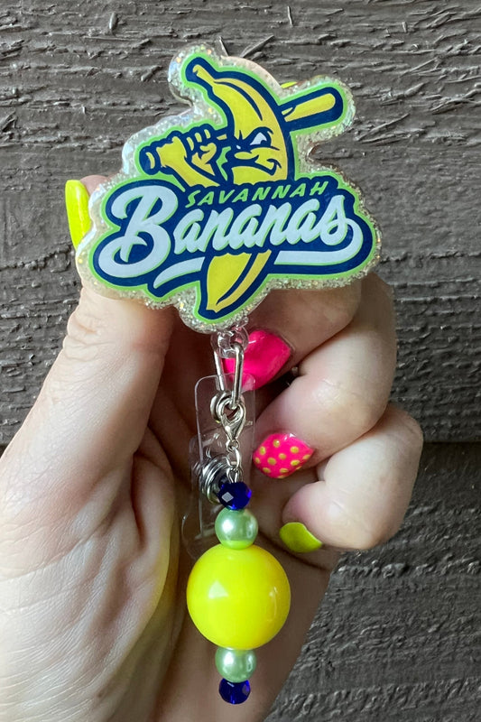 Hand holding a Savannah Bananas Badge Reel with coordinating badge bling.