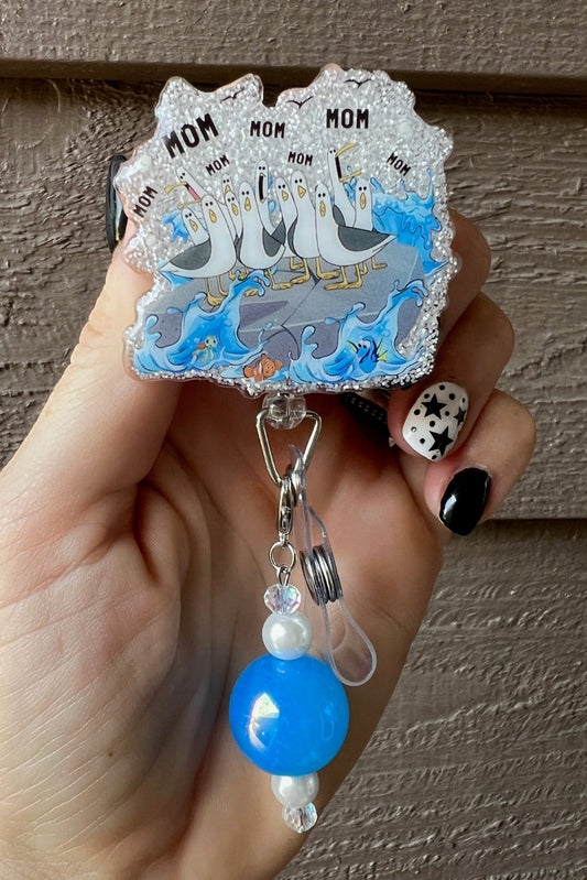 Hand holding Finding Nemo Badge Reel with Seagulls shouting "MOM MOM MOM" and coordinating badge bling.