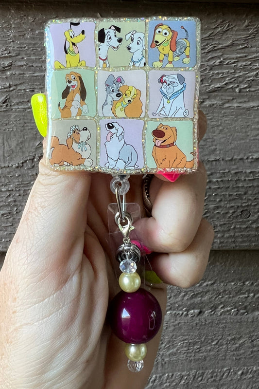 hand holding badge reel featuring 9 different squares with Disney dogs in each square and coordinating badge bling.