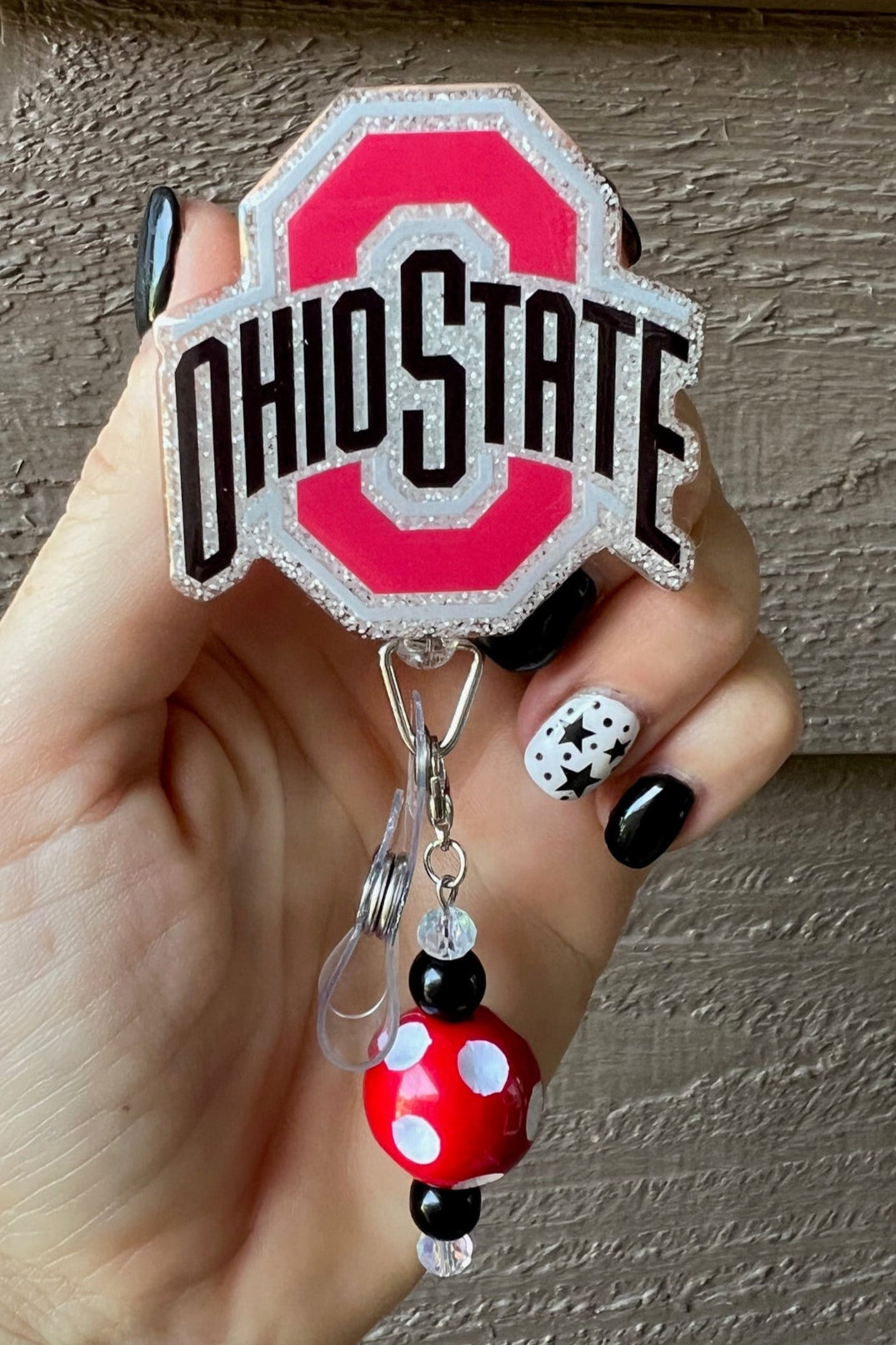 Hand holding Ohio State Buckeye Badge reel with coordinating badge bling.