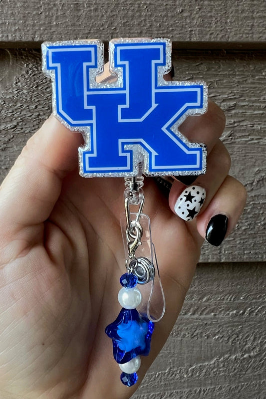 Hand holding University of Kentucky Wildcats badge reel with coordinating badge bling.