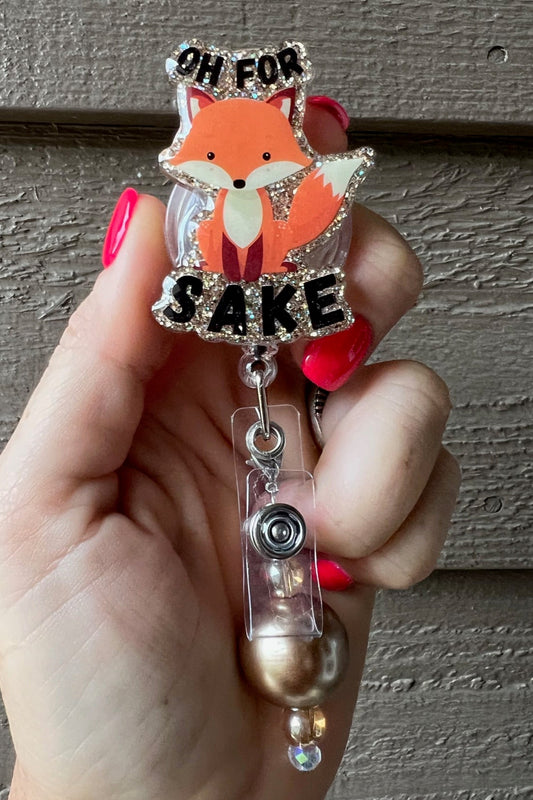 Fox badge reel that says "Oh for Fox Sake" on gold glitter background with coordinating badge bling.