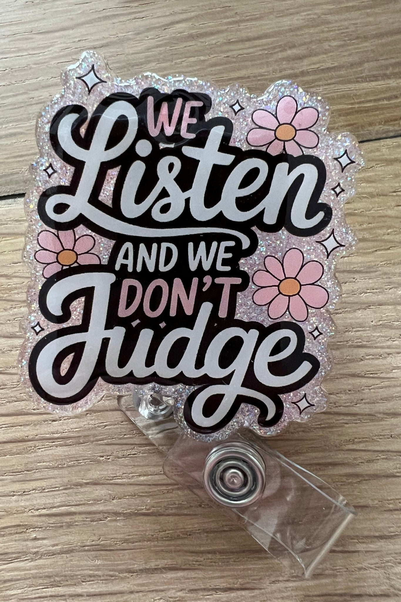 Pink Glitter Badge reel that says "We Listen and we don't judge" with flowers around the words