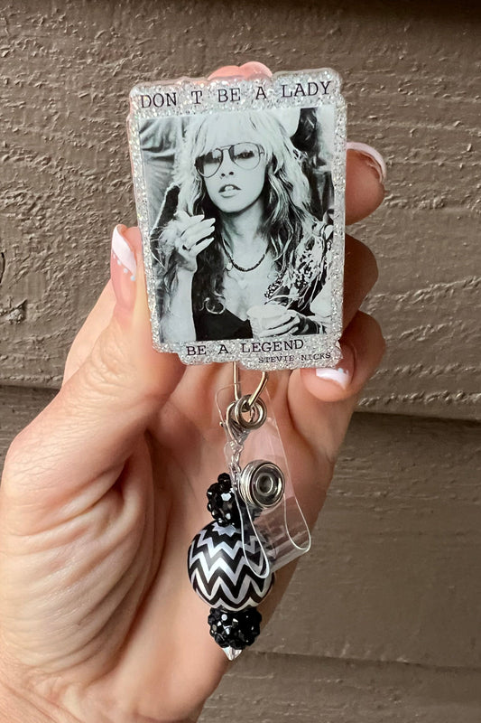 Black and white Stevie Nicks badge reel with glitter border and quote "Don't be a Lady, be a Legend."
