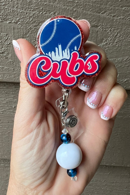 Red Glitter Cubs Baseball badge reel with blue and white beaded dangle.