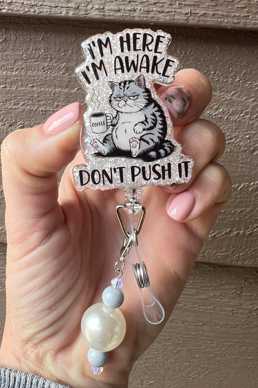 Funny cat badge reel with glitter border and coffee cup, reading "I'm here, I'm Awake, don't push it," paired with coordinating badge bling.