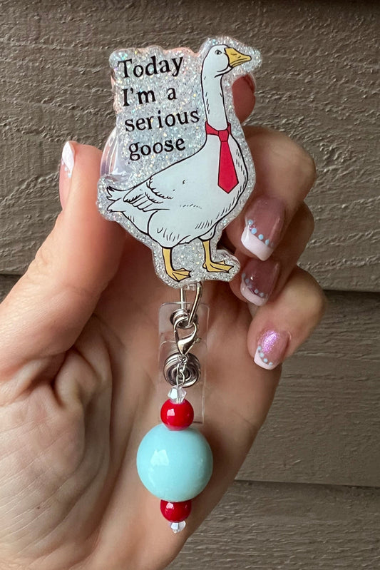Goose with necktie badge reel that says "Today I'm a serious goose" over light blue glitter.