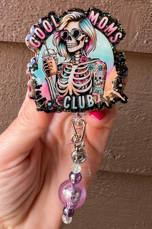 Cool Moms Club badge reel with skeleton with rainbow hair, tattoos, and an iced coffee with coordinating badge bling.