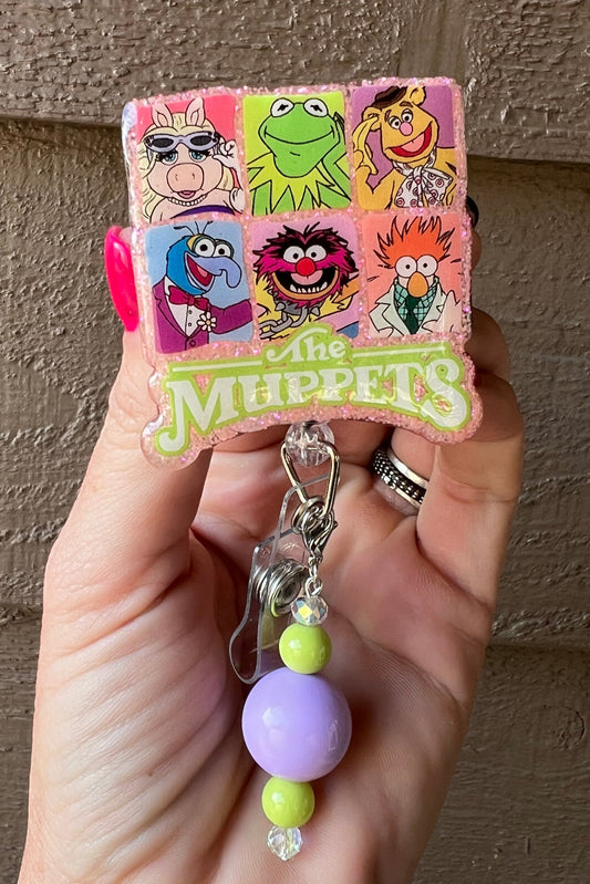 Glittery badge reel featuring The Muppets character collage with purple and lime green beaded dangle