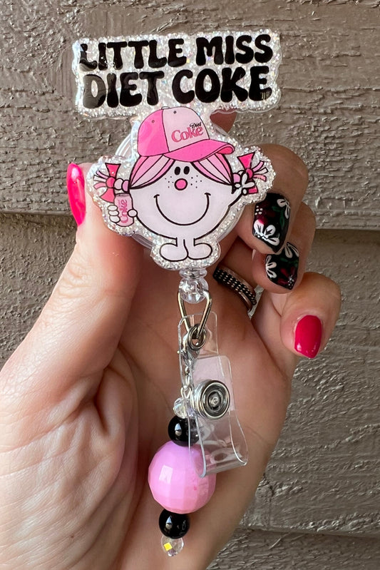 Glittery Little Miss Diet Coke Badge Reel with pink hat and black/pink beaded dangle.
