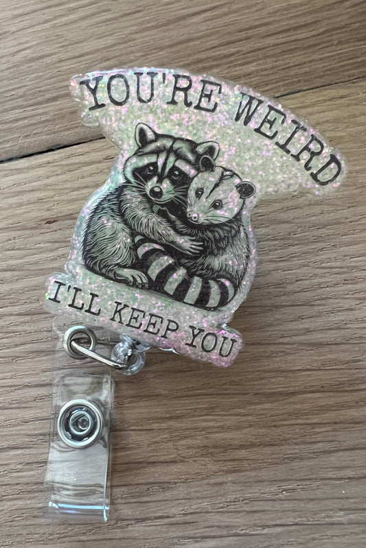 Funny Raccoon and possum badge reel that says "you're weird, I'll keep you"
