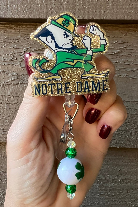 Notre Dame badge reel with gold glitter border and shamrock beaded dangle
