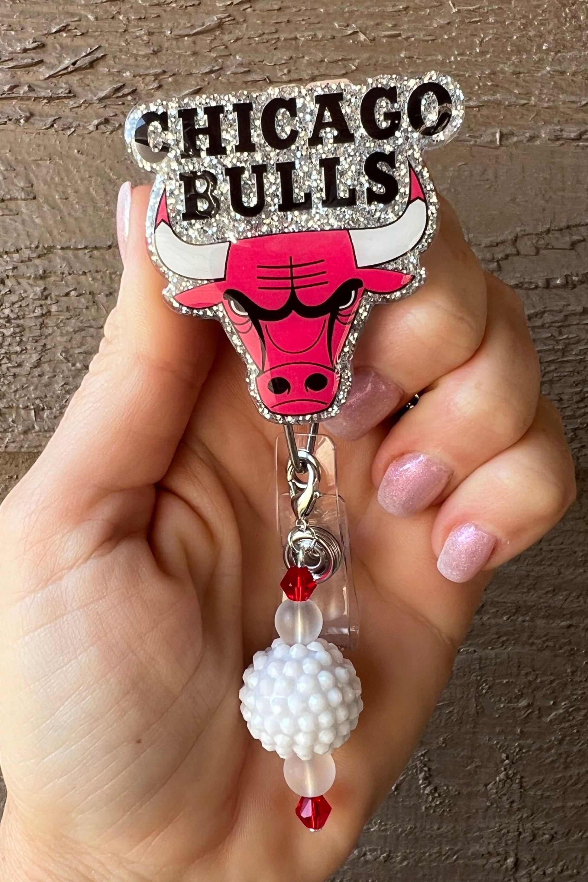 Chicago Bulls badge reel with silver glitter behind the logo and a white and red beaded dangle.