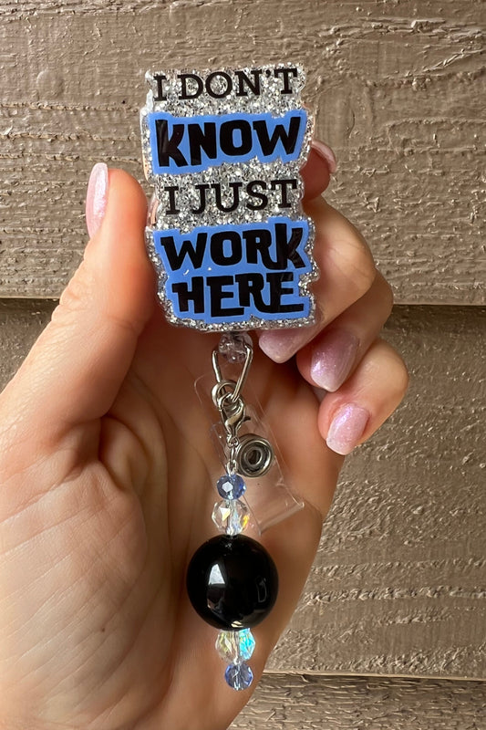 Glittery badge reel with the phrase “I Don’t Know, I Just Work Here,” paired with black and crystal beaded charm. Perfect for adding humor to work badges.
