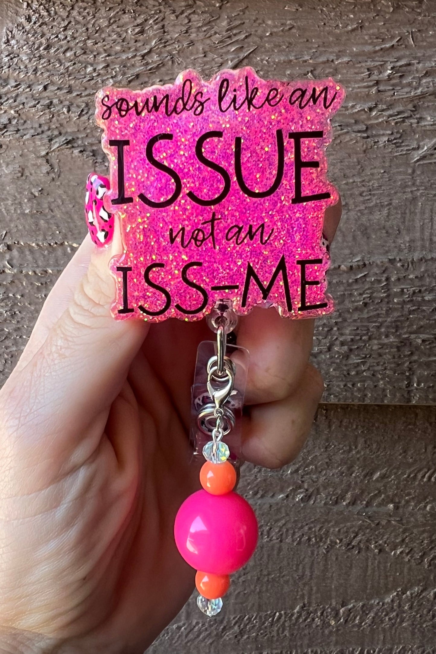 Hot pink glitter badge reel with the phrase “Sounds Like an Issue, Not an Iss-Me,” featuring neon pink and orange beaded charm, perfect for office humor and snarky style.